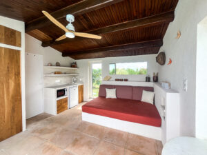 Pool house avec banquette maçonnée et kitchenette, aménagement durable pour maison de vacances.